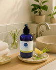 Blue bottle of lemongrass liquid hand soap on bathroom counter with lemon slices and lemongrass stalks for a refreshing, moisturizing cleanse