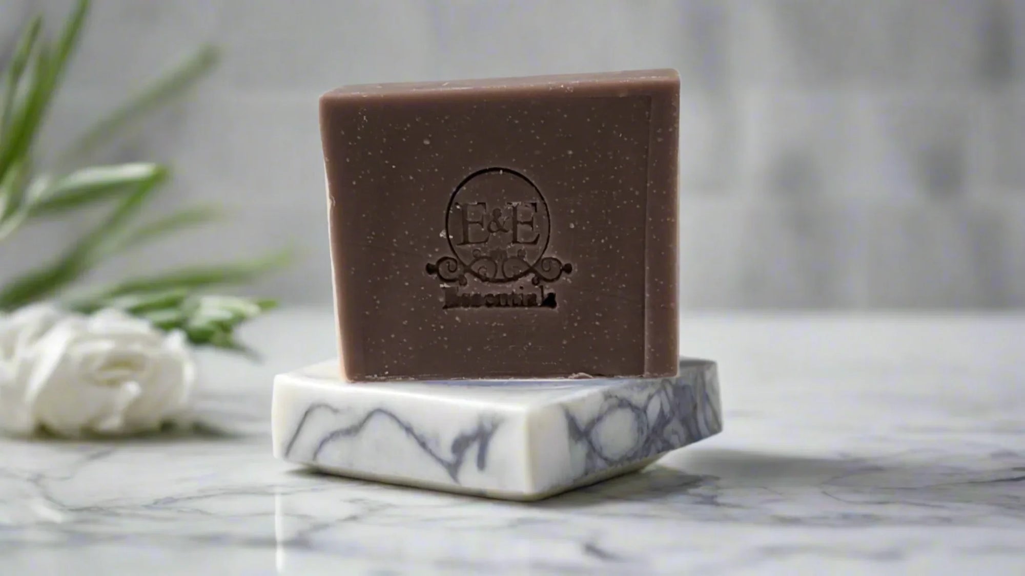Lavender bar soap on marble soap dish with fresh sprigs nearby.