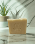 aloe & shea butter bar soap on marble surface, plant in background