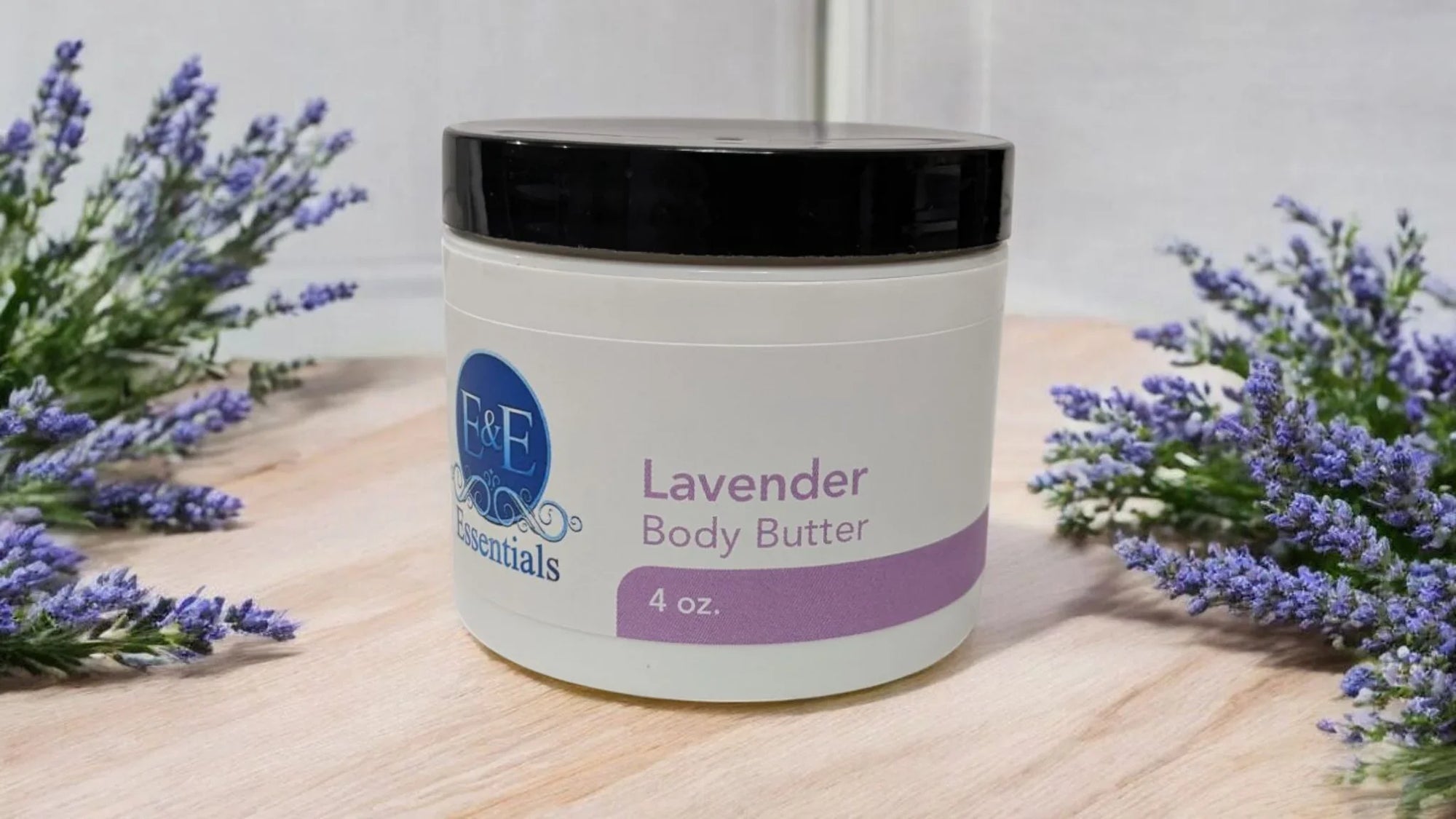 Lavender Whipped Body Butter jar amidst fresh lavender sprigs on a wooden surface.