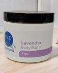 Lavender Whipped Body Butter jar amidst fresh lavender sprigs on a wooden surface.