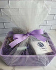 Gift basket with oatmeal and honey soap, peppermint lip balm, lavender body butter in a purple storage bin, decorated with a purple ribbon.
