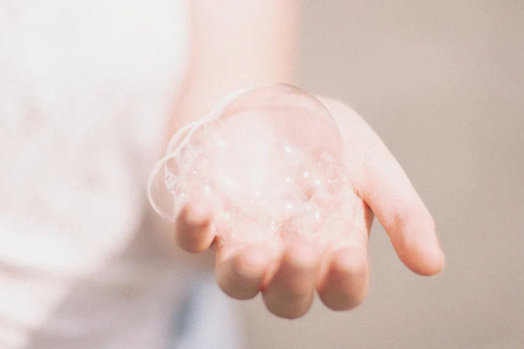 Hand holding delicate soap bubbles, illustrating cold process soap making.