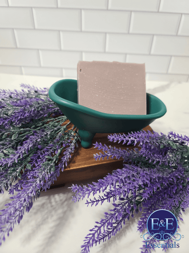 Lavender soap in a green dish surrounded by lavender sprigs, showcasing its soothing and healing benefits for skin.