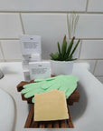 Aloe & Shea Butter Bar Soap displayed with gloves and a green plant on a counter