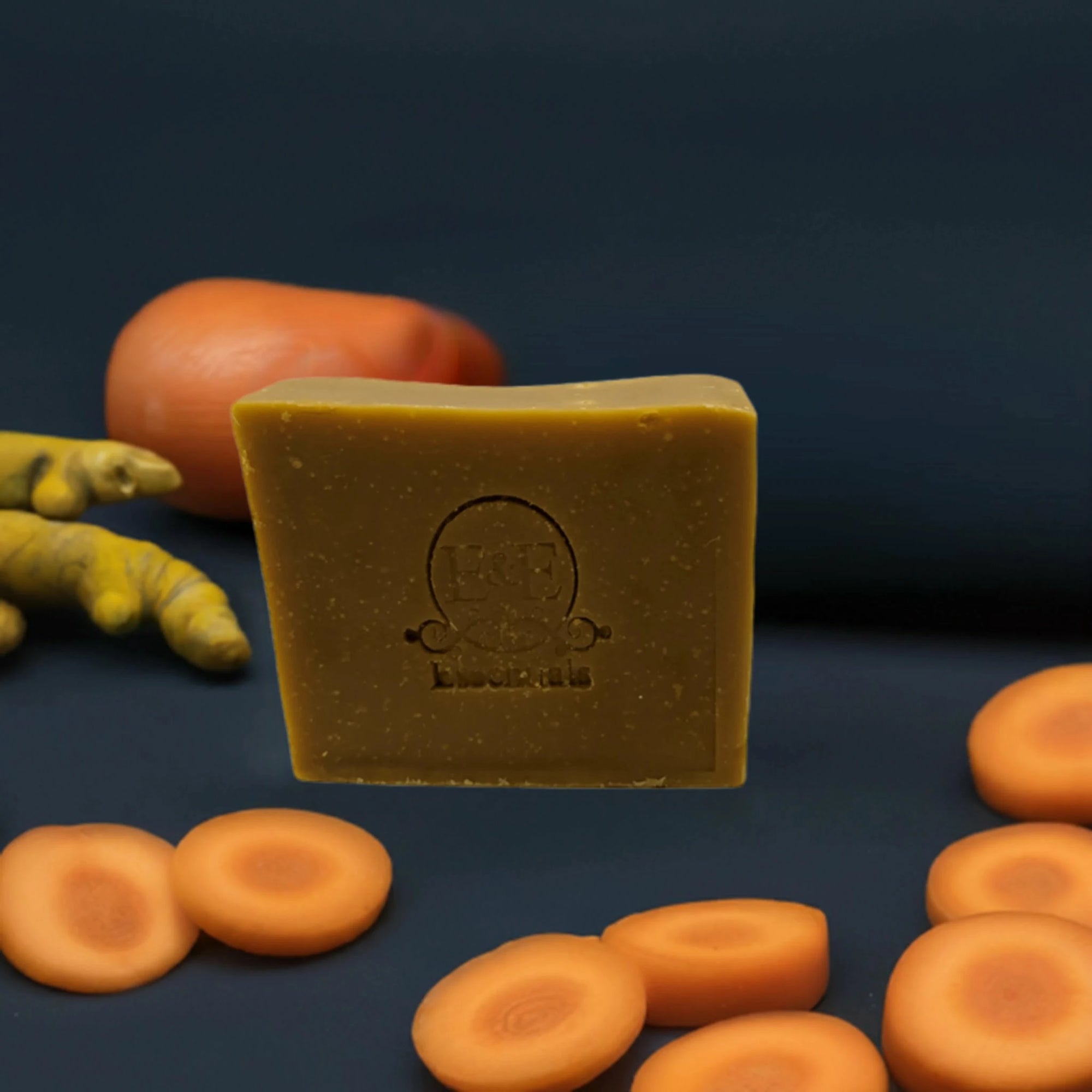 Carrot & Turmeric Bar Soap accompanied by carrots and turmeric roots