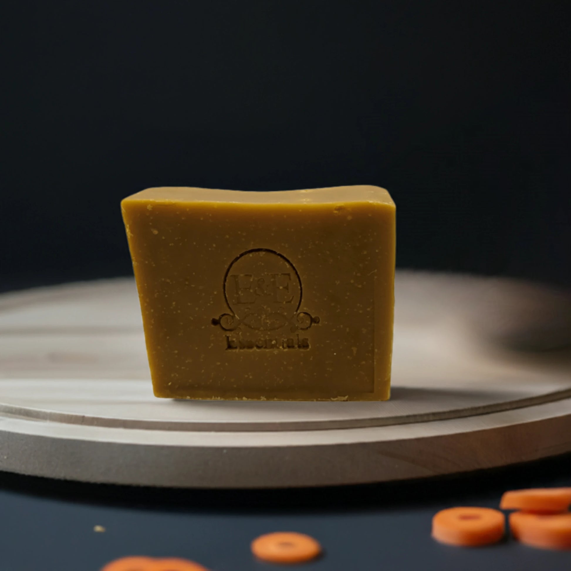 Carrot & Turmeric Bar Soap displayed on a wooden board alongside fresh carrots