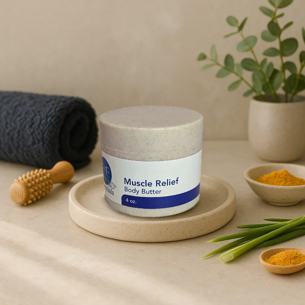 Muscle Relief Body Butter jar on beige plate with turmeric powder, green leaves, and wooden massage tool nearby in spa setting