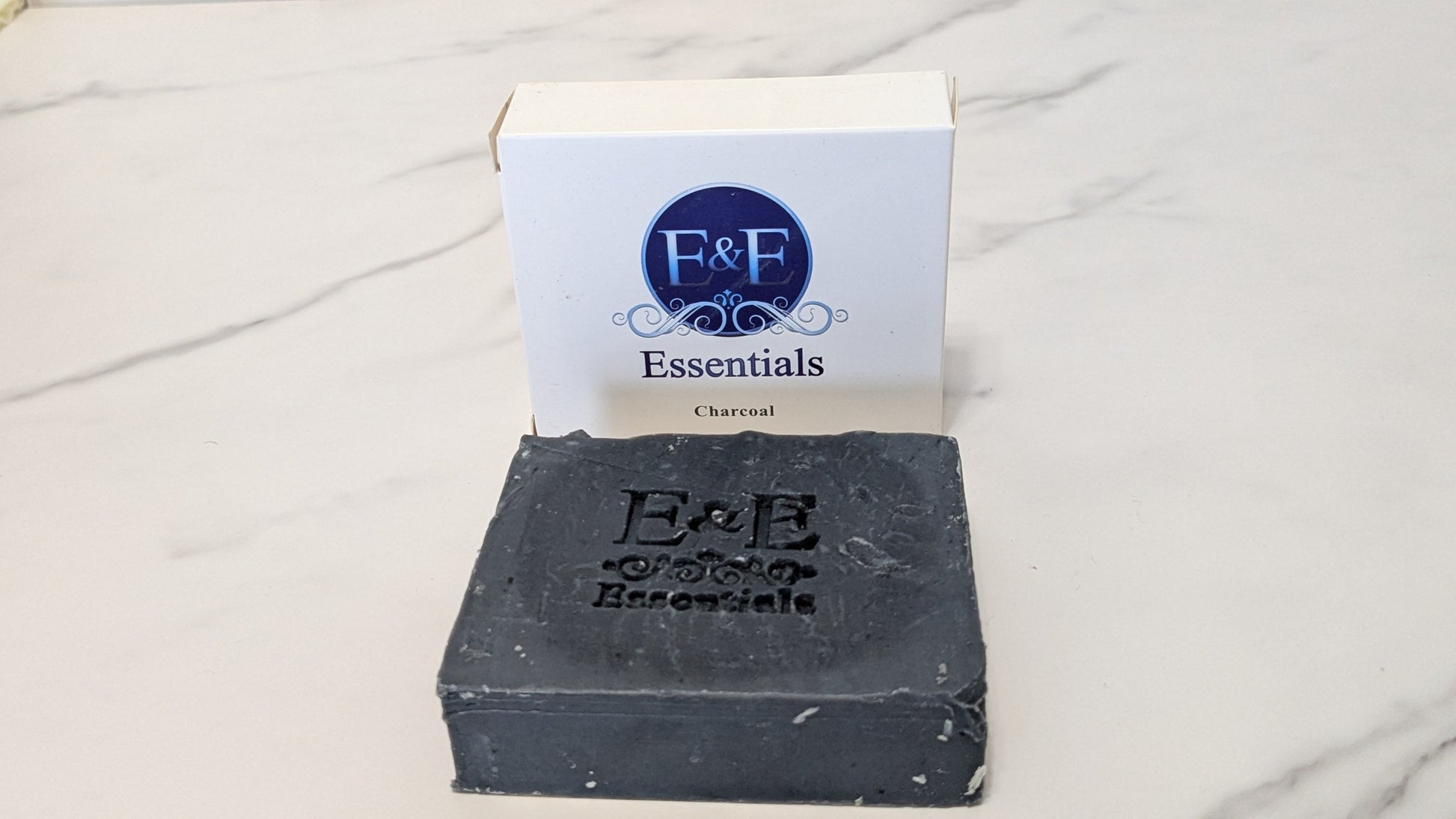 Packaged charcoal bar soap next to its box with a black label