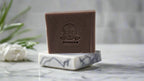 Lavender bar soap on marble soap dish with fresh sprigs nearby.