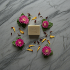 Bar of soap with pink flowers and yellow petals on a marble surface