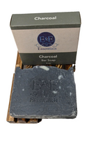 activated charcoal soap bar on a wooden soap dish with packaging in the background