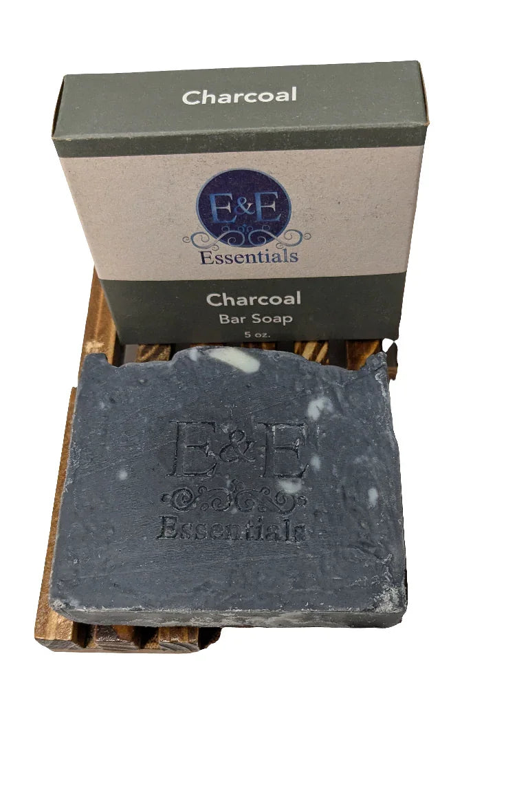 activated charcoal soap bar on a wooden soap dish with packaging in the background