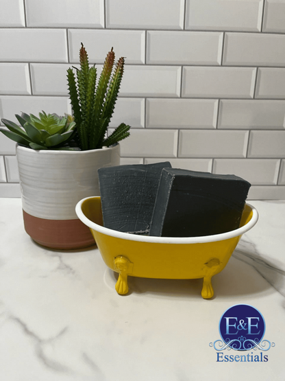 Charcoal bar soap placed beside a yellow bathtub, ready for use