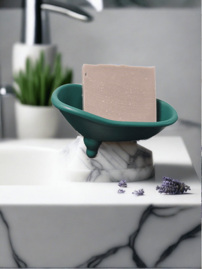 Lavender bar soap in a dish on a marble surface with lavender sprigs nearby