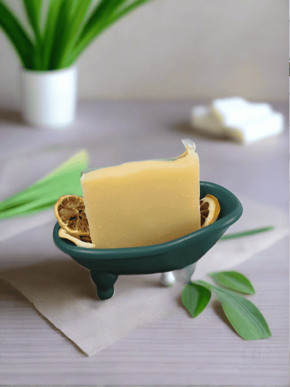 Lemongrass bar soap displayed in a green ceramic dish with decorative leaves