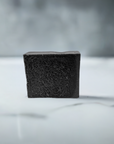 Close-up of charcoal bar soap on a pristine white countertop