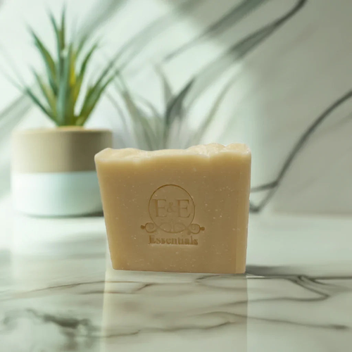 aloe & shea butter bar soap on marble surface, plant in background