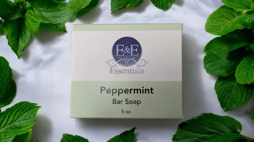 Peppermint Bar Soap packaging surrounded by fresh mint leaves.