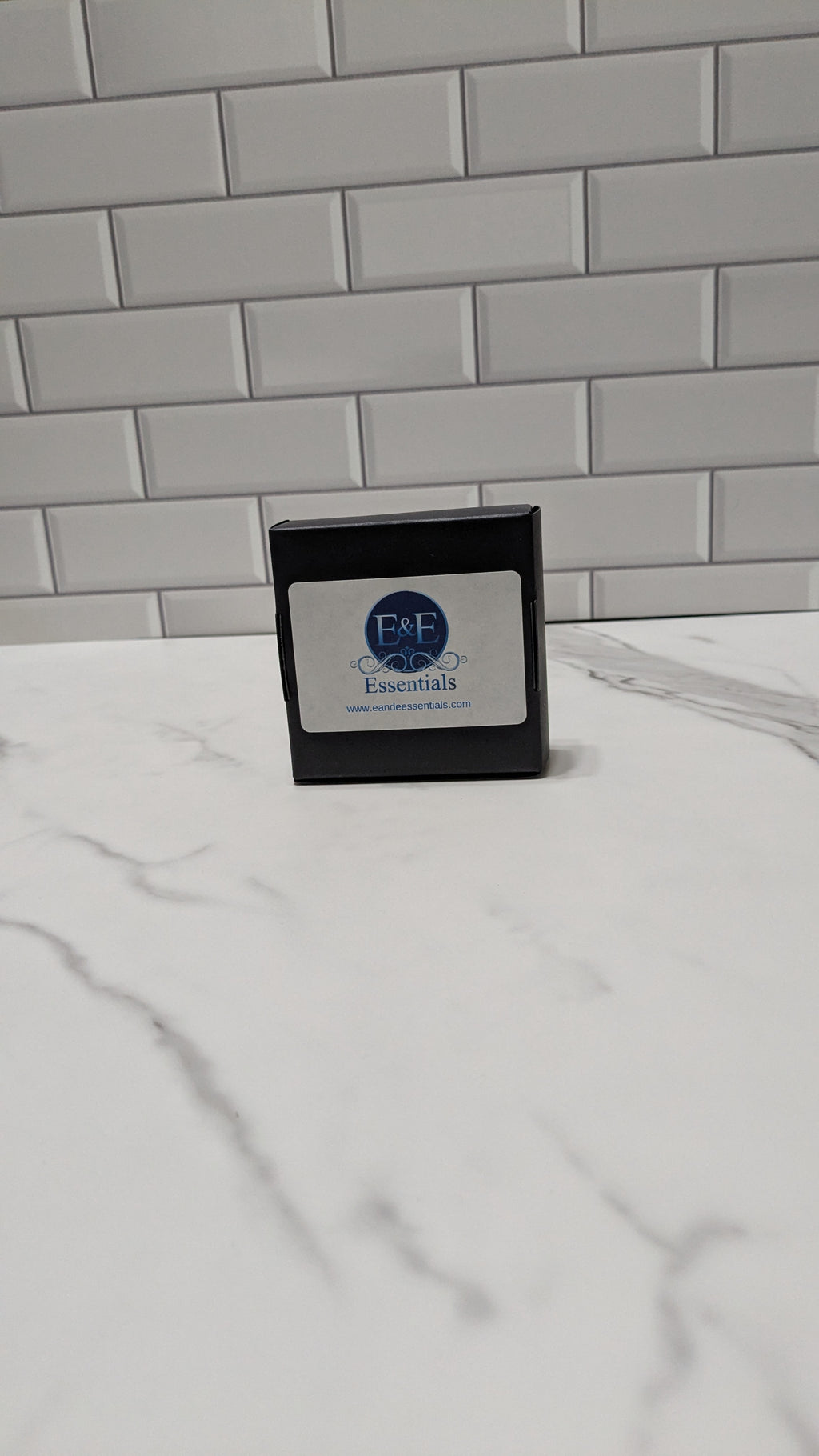 Small black box with a label on a white surface against a gray tiled wall.