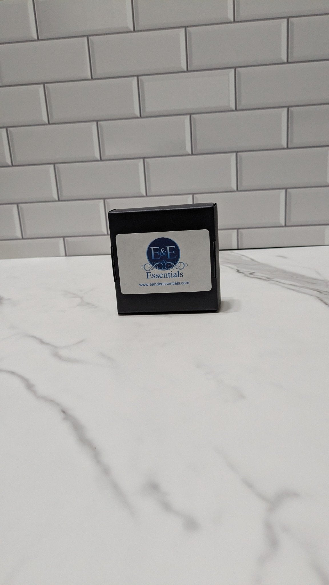 Small black box with a label on a white surface against a gray tiled wall.