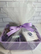 Gift basket with oatmeal and honey soap, peppermint lip balm, lavender body butter in a purple storage bin, decorated with a purple ribbon.