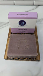 Lavender bar soap with packaging on a wooden soap dish, promoting stress relief and aromatherapy benefits.