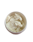 Vanilla-scented body butter in an open container on a marble surface